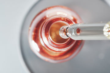 Glass dropper with rose-coloured serum — PDRN cellular renewal